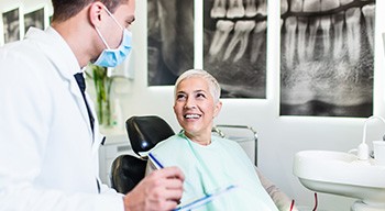 Dentist taking notes on clipboard with smiling patient