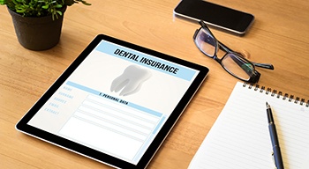 A tablet that reads Dental Insurance and glasses nearby