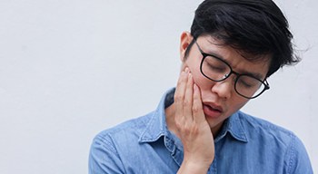 a man touching his jaw due to TMJ pain
