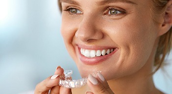 Woman smiling while holding teeth whitening tray